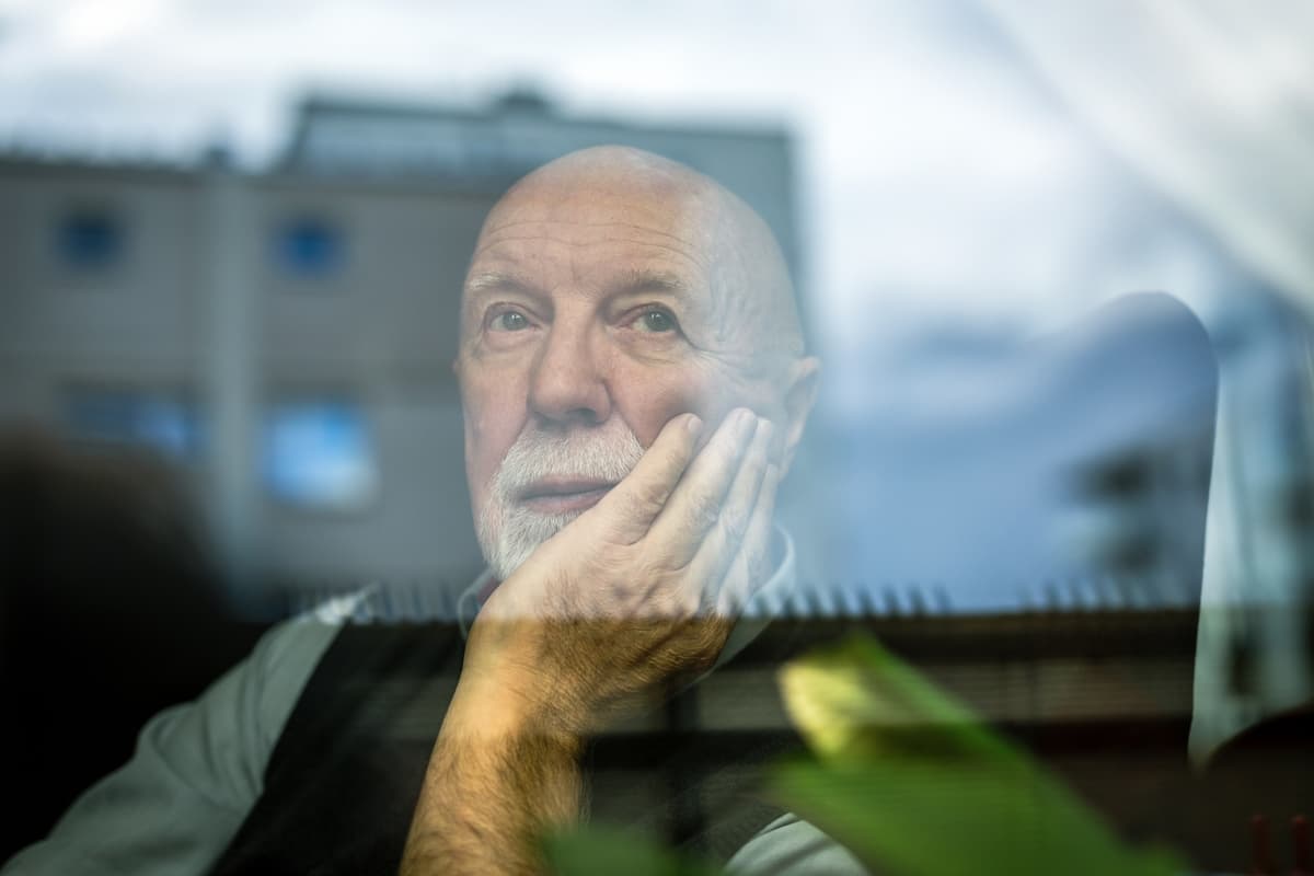 Retrato do homem sênior pensativo olhando através da janela