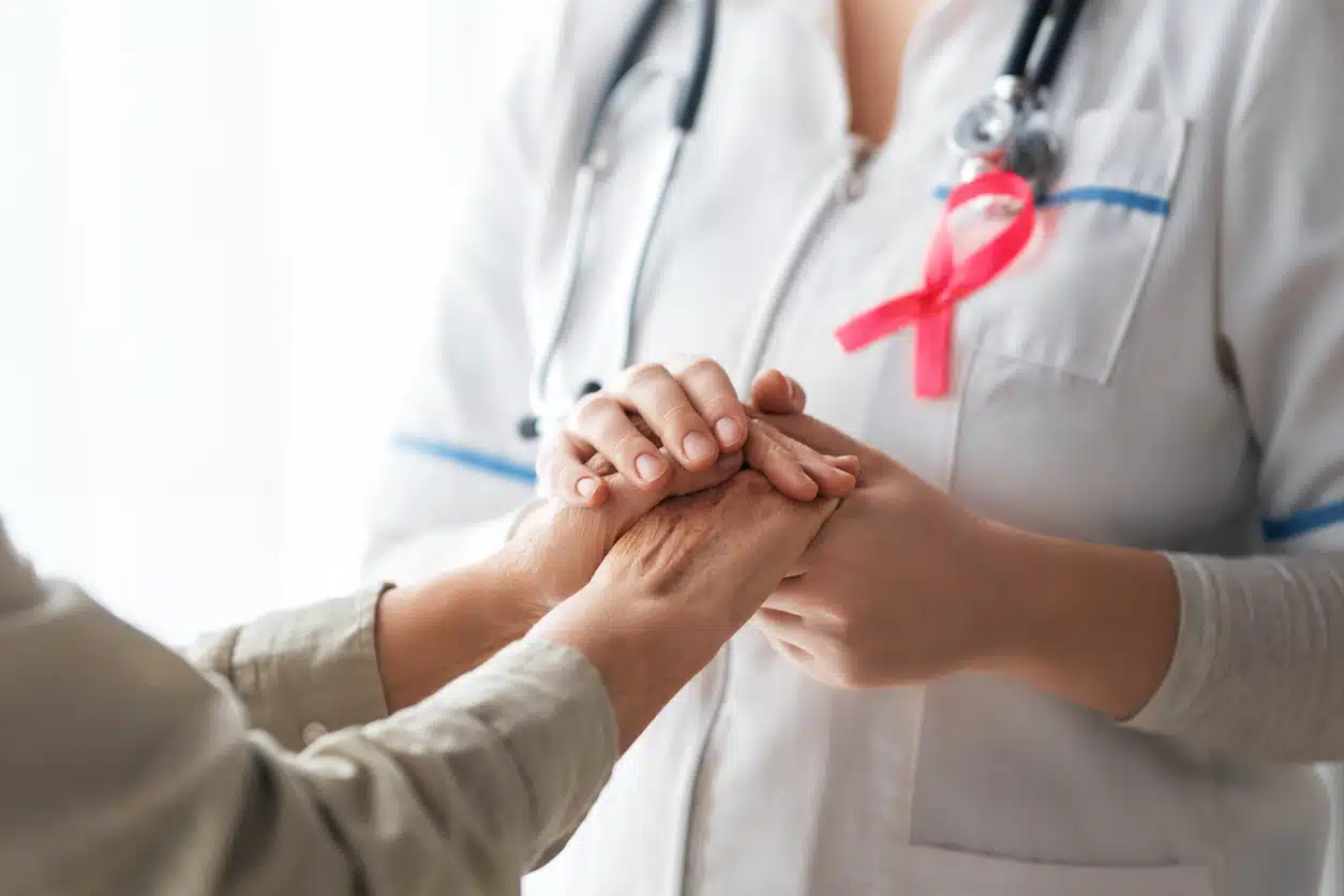 enfermeira prestando suporte a paciente com cancer maos em destaque
