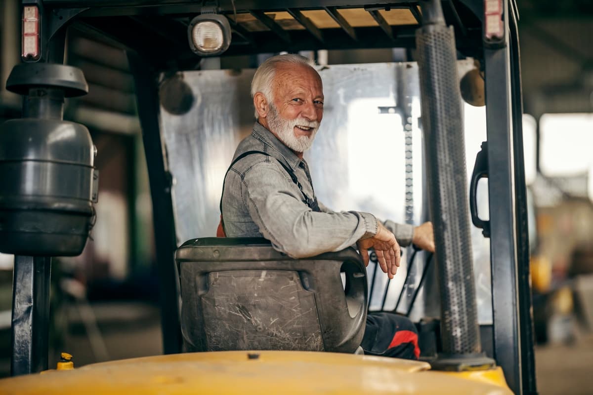 homem idoso operador de máquina trabalhando olhando de costas e sorrindo