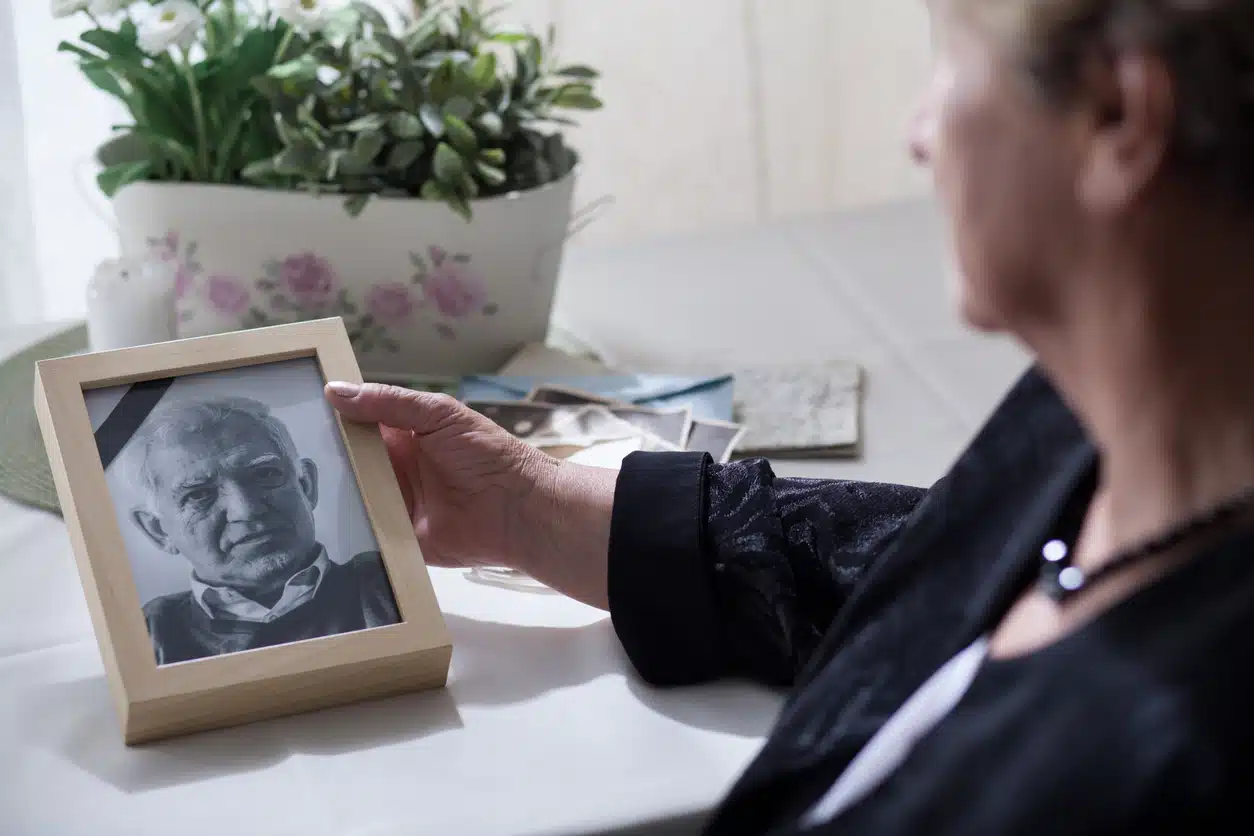 mulher idosa olhando para porta retrato de marido falecido