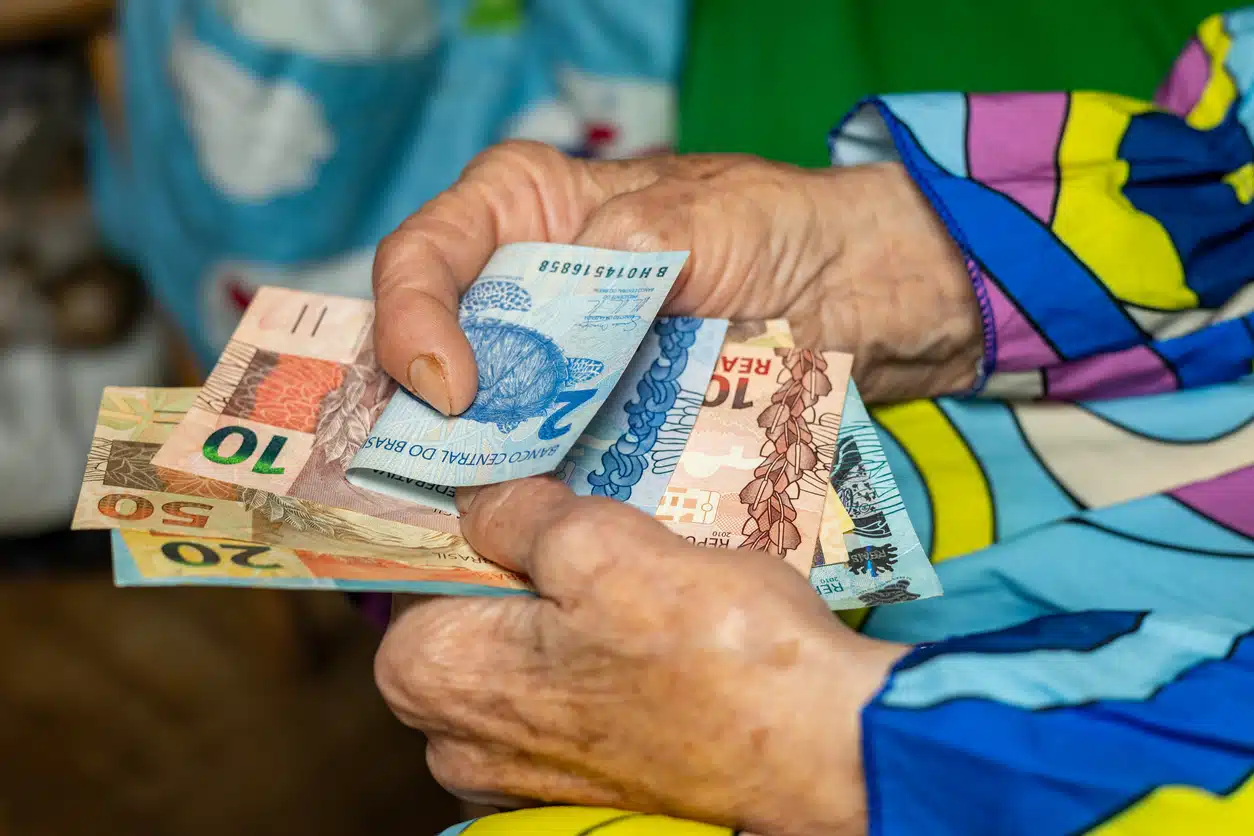 Mulher sênior segurando reais brasileiros nas mãos