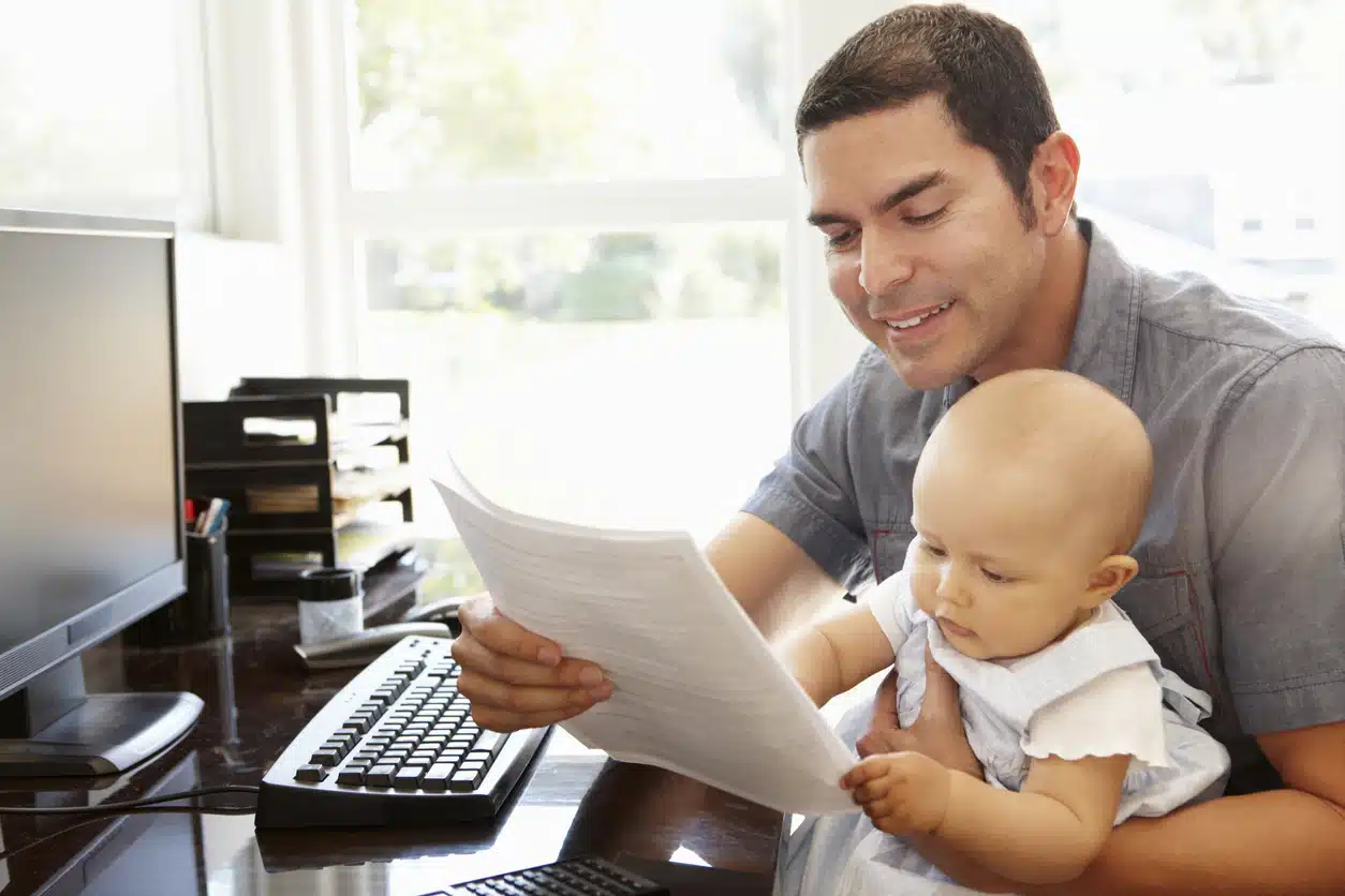 pai trabalhando com filha bebê no colo