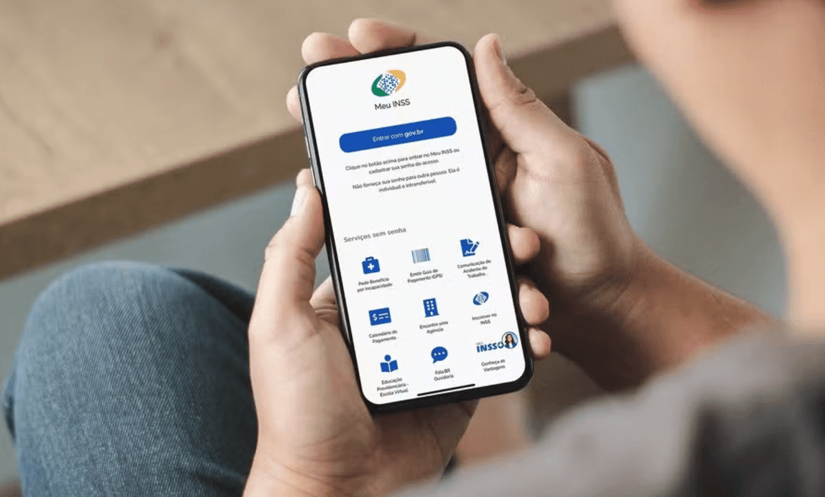 destaque de maos segurando celular com tela do meu inss