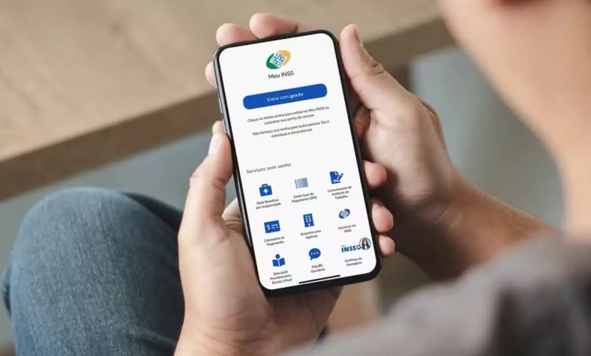 destaque de maos segurando celular com tela do meu inss