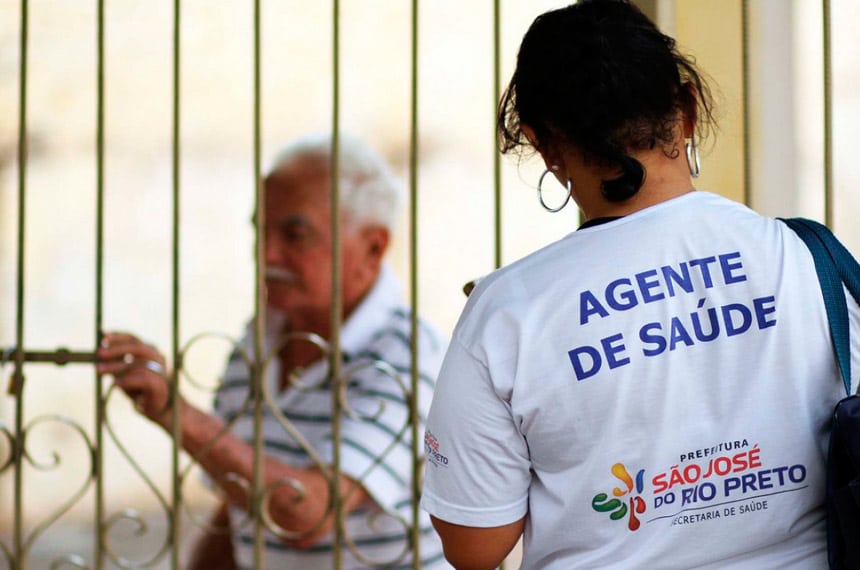 agente de saúde de costas, na frente da casa de um idoso
